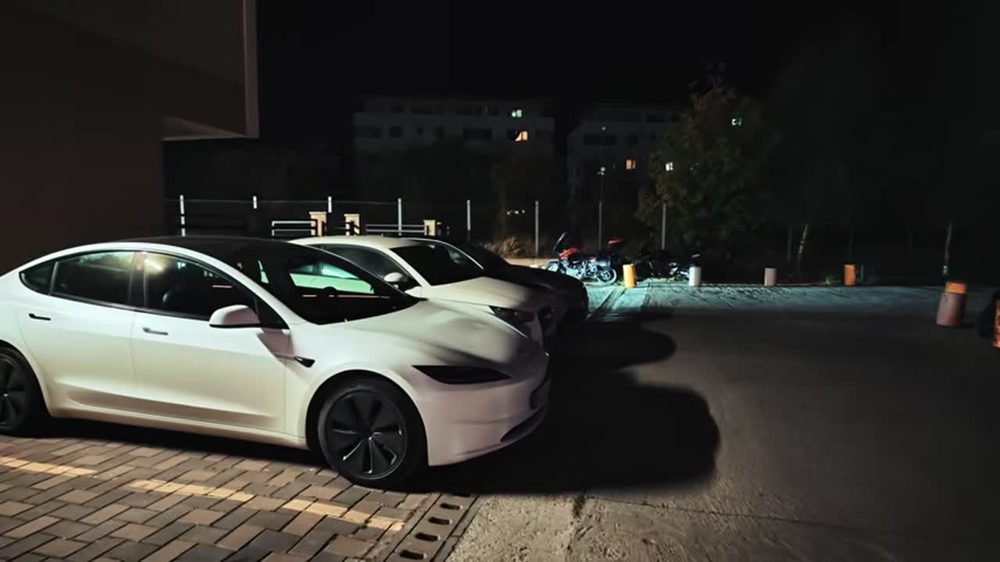 Tesla Model 3 albă parcată noaptea, cu luminile aprinse în Modul Halloween