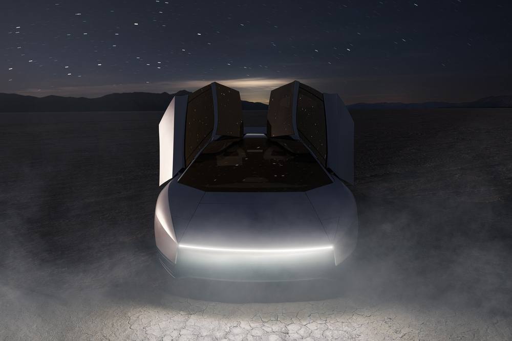 The new white Tesla Roadster seen from the front with its doors raised, on a desert lakebed at night