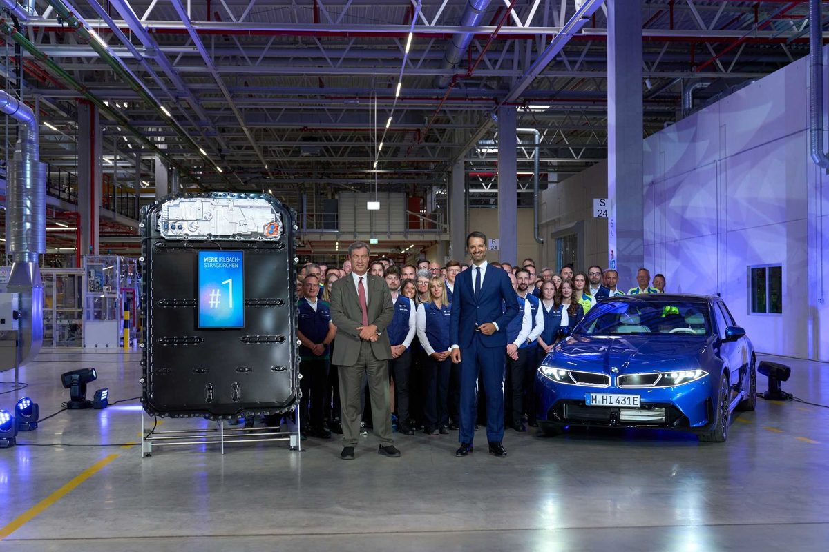 Prima baterie de serie produsă la Irlbach-Straßkirchen, expusă lângă un BMW i3 nou albastru și echipa fabricii, la ceremonia de deschidere