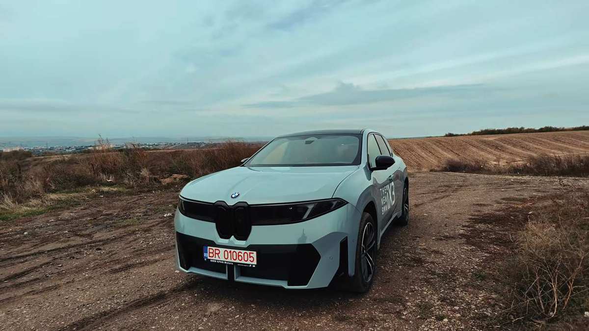 BMW iX3 40 Neue Klasse, verde-mentă, fotografiat din față pe un drum de câmp