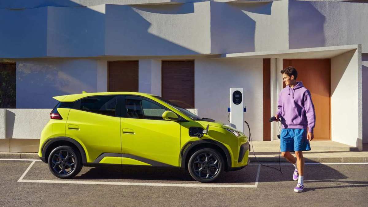 Lime green BYD Dolphin Surf charging in front of a house