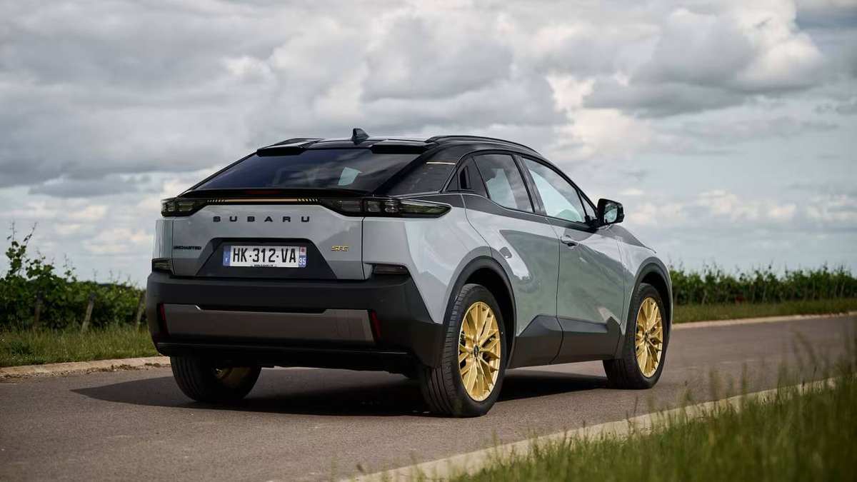 Grey Subaru Uncharted with gold wheels, seen from the rear on a country road