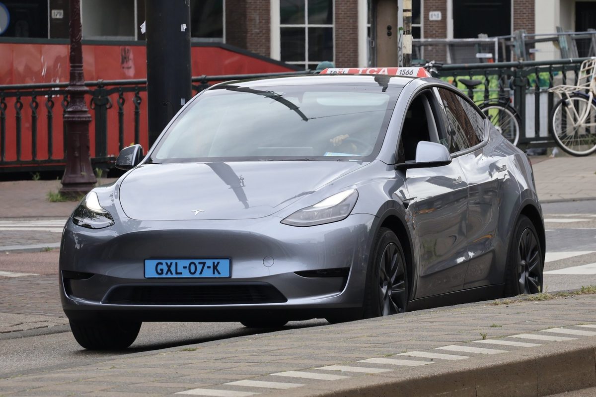 Tesla Model Y gri pe o stradă din Amsterdam, cu biciclete parcate în fundal