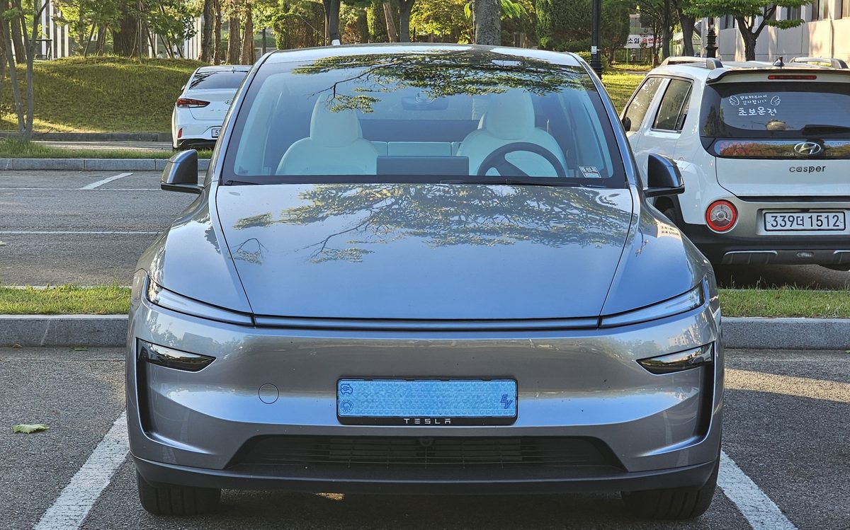Tesla Model Y nou, în culoarea Quicksilver, văzut din față într-o parcare