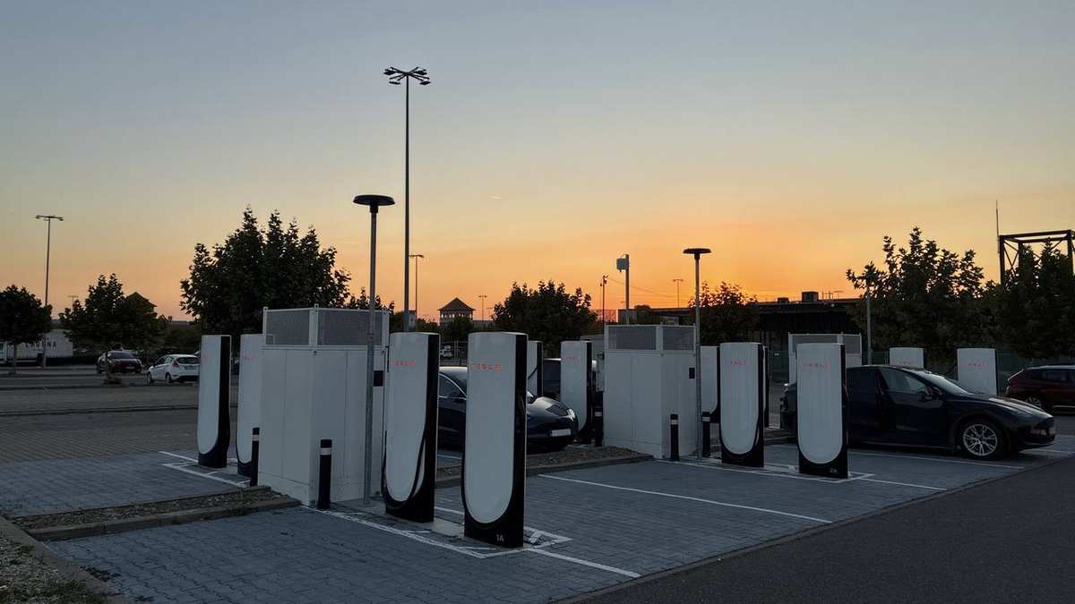 Tesla V4 Supercharger posts at the Bucharest West site at sunset, with a Tesla charging